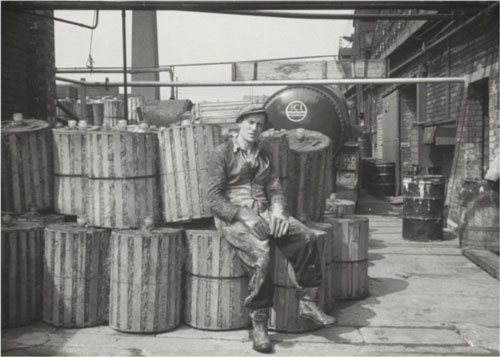 Bill Sheard sitting on ACPA kegs, 1959.